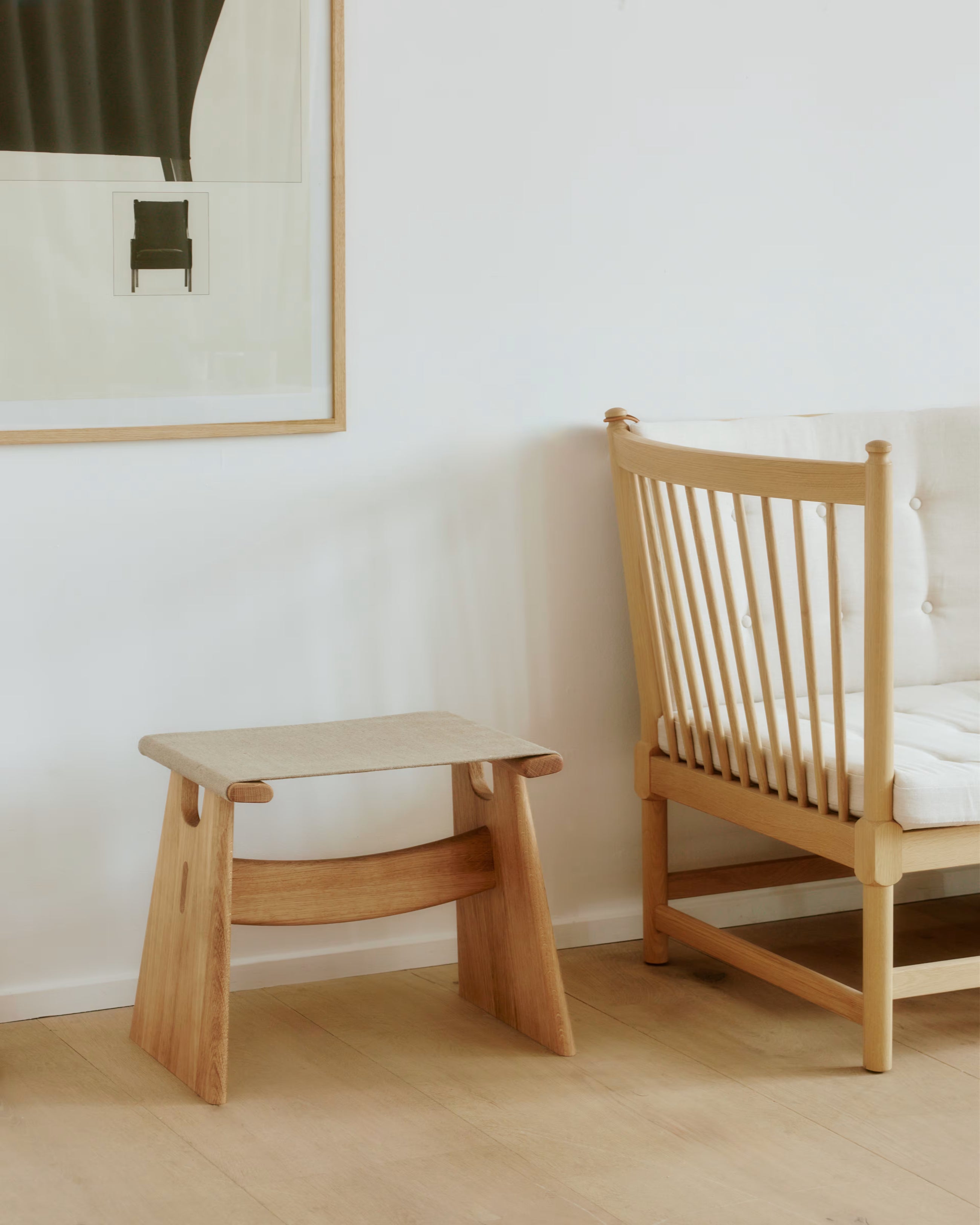 Lysoljet eik Seto Stool med naturcanvas plassert ved siden av den ikoniske Spoke Back Sofa, i et skandinavisk inspirert interiør, viser krakkens tidløse design og harmoniske samspill med andre møbler.