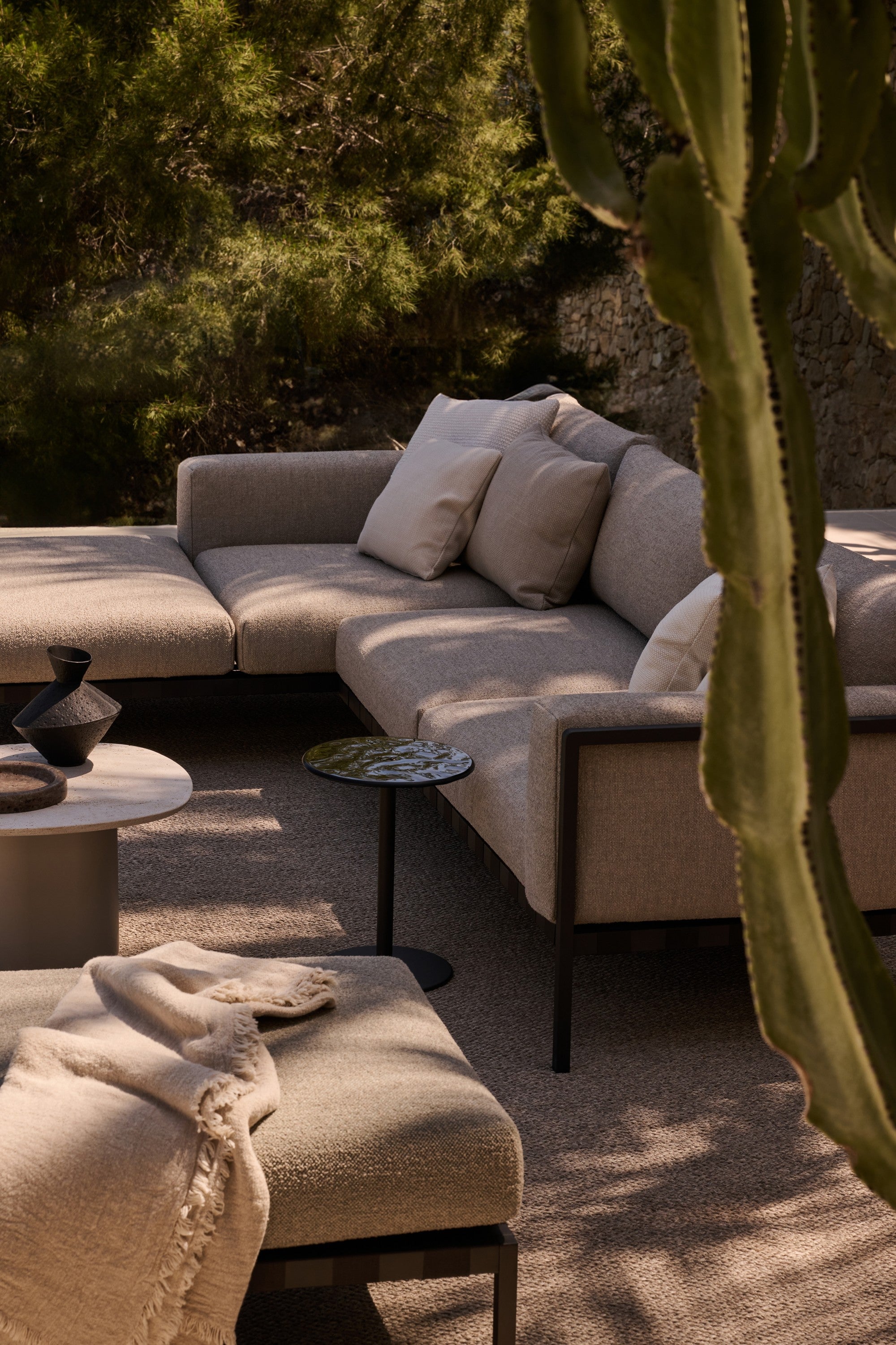 Mare sidebord fra Tribu plassert ved en utendørs sofagruppe med moderne loungemøbler, der det slanke bordet fungerer som et funksjonelt avlastningsbord i et stilrent uterom.