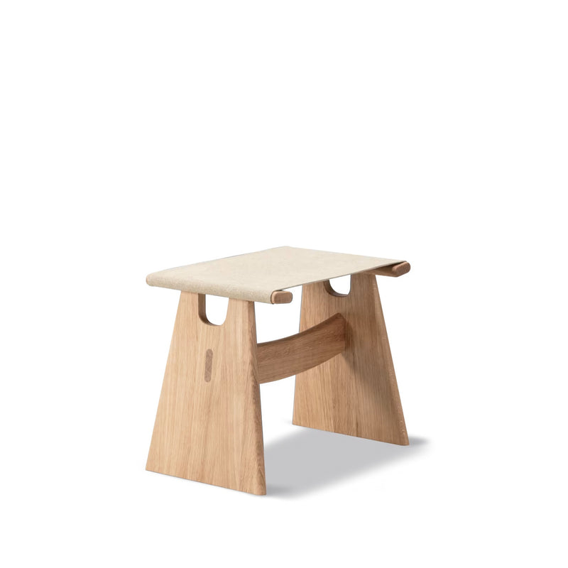 Lysoljet eik Seto Stool med naturfarget canvas, isolert på hvit bakgrunn, viser stolens klassiske krakkhøyde og H-struktur.